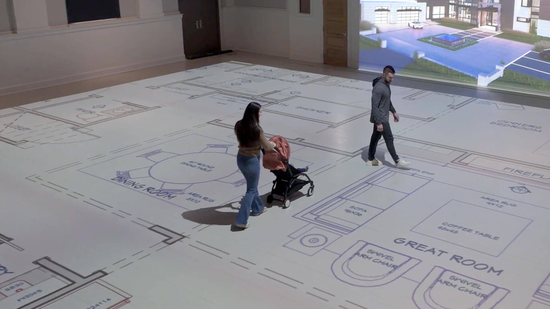 Young couple with stroller walking through their plans with a rendering of the house exterior projected onto the wall
