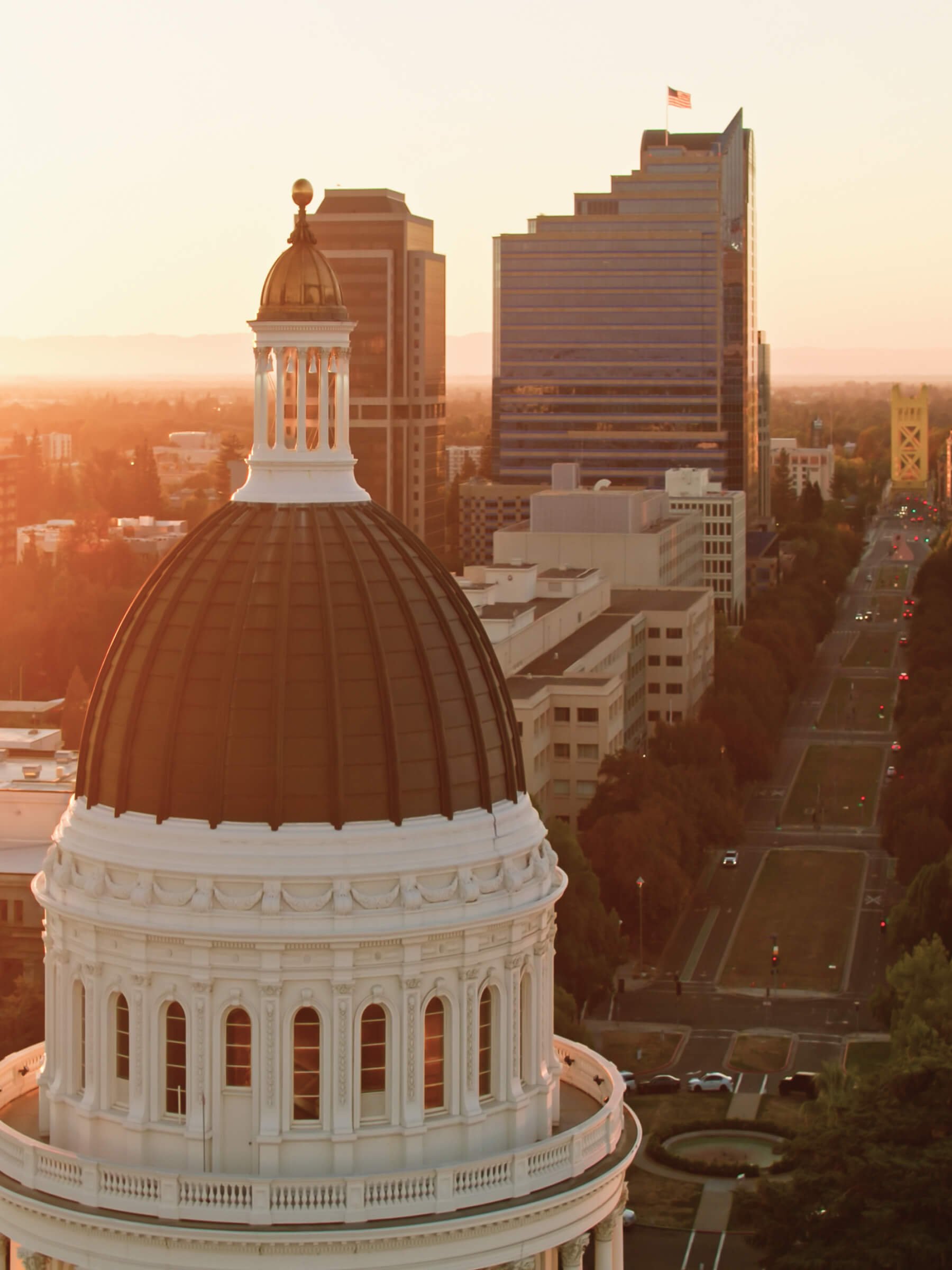 High-angle view of an ornate domed building with a city skyline in the background during sunset.