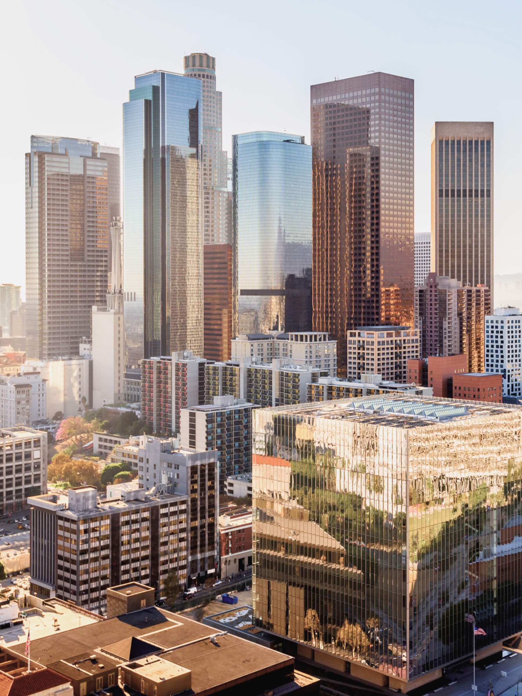 City skyline with high-rise office buildings and skyscrapers, some with glass facades reflecting neighboring structures, in bright sunlight